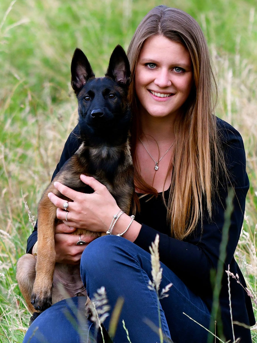 Amaryllis accroupie avec un jeune chien dans l’herbe